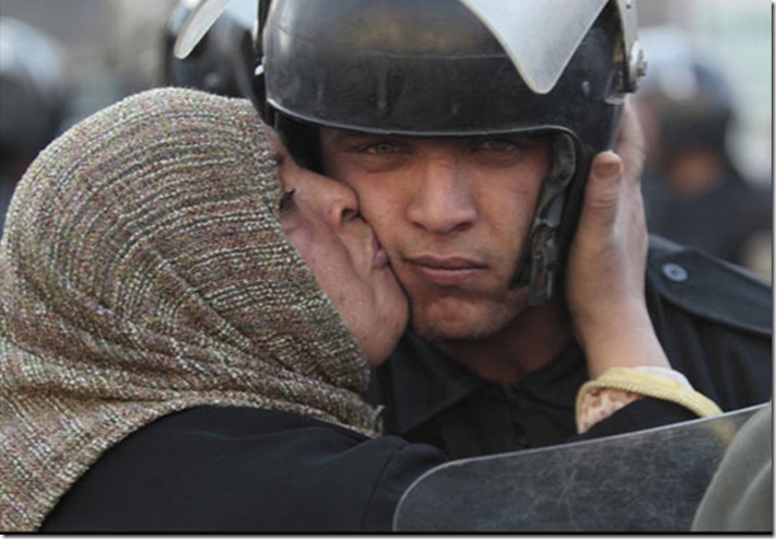 16. Egypt, 2011 - Egyptian woman kisses a policeman during the revolution against the Mubarak Government